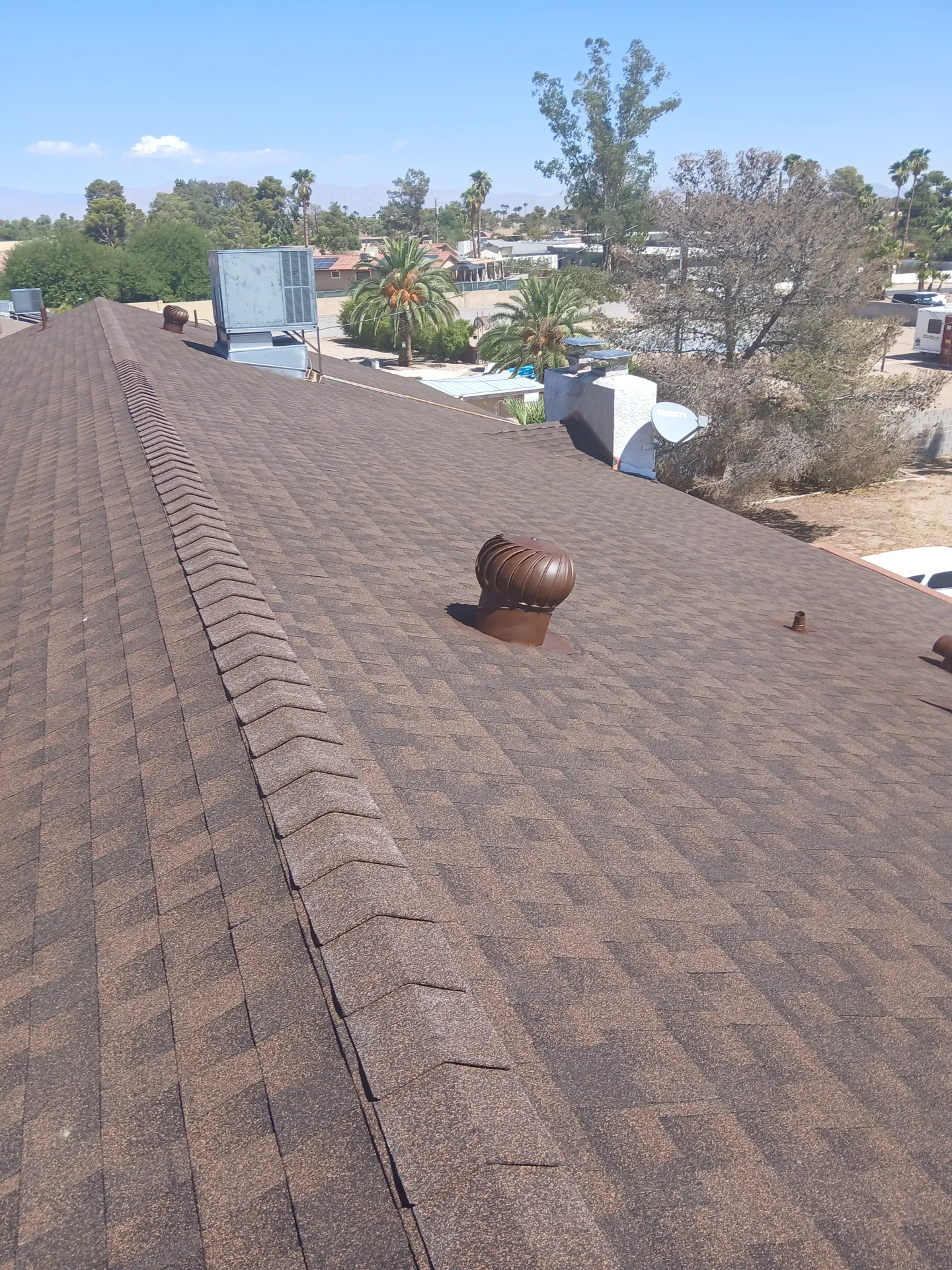 Finished brown shingle roof by Lopez Roofing under a blue Las Vegas sky